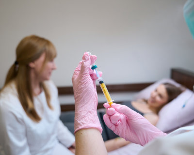 medical professional wearing pink gloves holding a syringe