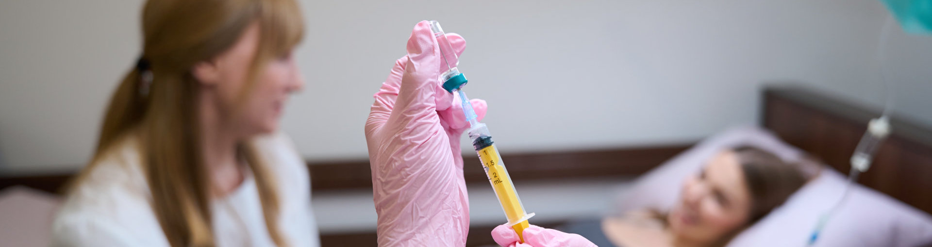 medical professional wearing pink gloves holding a syringe